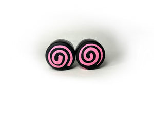 round roller skate toe stop in a black color with a pink swirl through it on a white background.