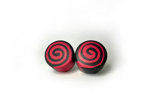 round roller skate toe stop in a black color with a red swirl through it on a white background.