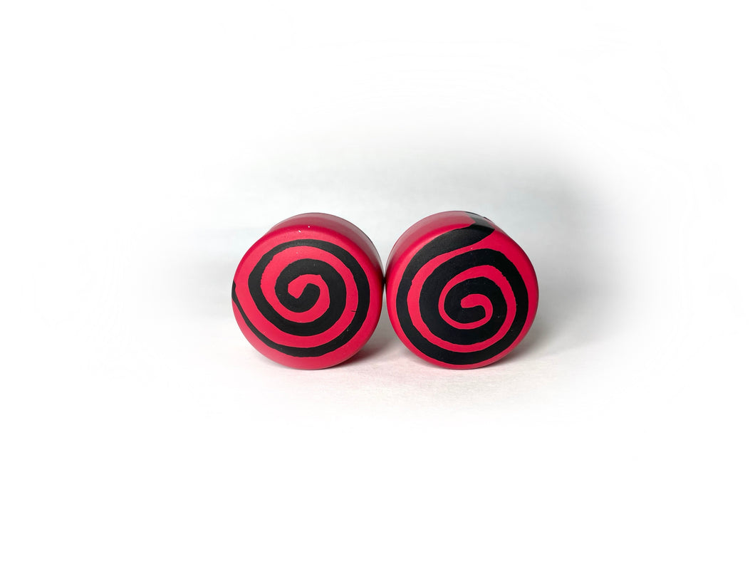 red color round roller skate toe stop with a black swirl through it on a white background. 