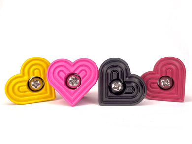 heart shaped roller skate toe stop on a white background. far left toe stop color is yellow. center left is a pink color. center right is a black color. far right is a red color.